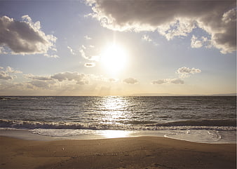 Sunlit Ocean Beach with Clouds and Golden Hour Light
