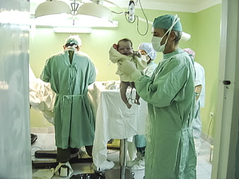 Newborn baby held by doctor in hospital delivery room