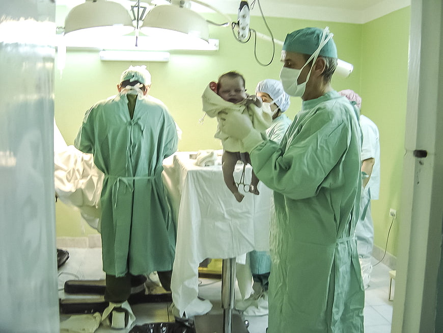 Newborn baby held by doctor in hospital delivery room