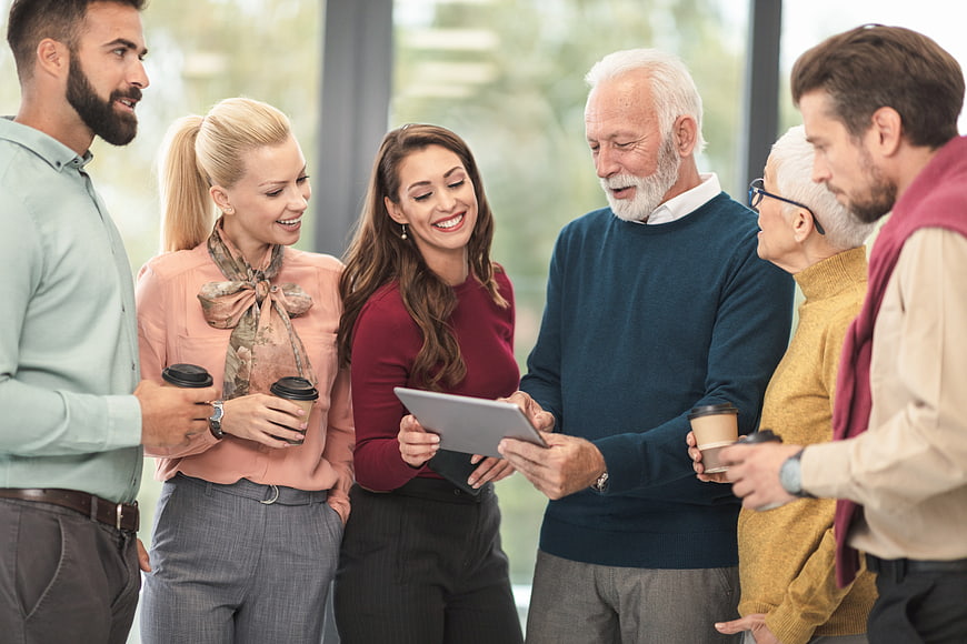 Diverse multi-generational business team discussing tablet