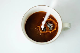 Top View of Milk Splashing into Black Coffee Cup