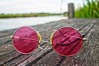 Pink round sunglasses on weathered wooden dock