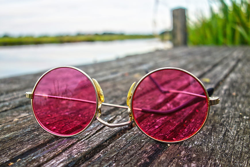 Pink round sunglasses on weathered wooden dock