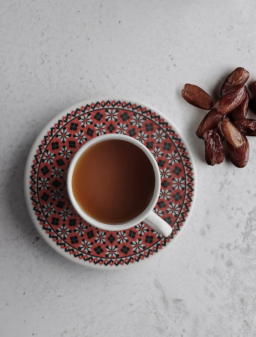 Top View of Coffee Cup with Dates on Patterned Saucer