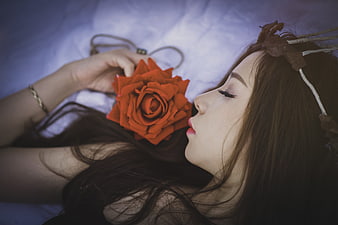 Asian woman sleeping with red rose on white bed