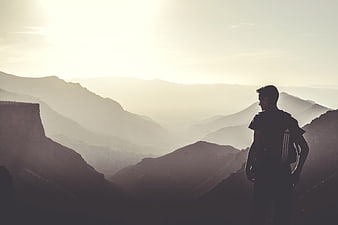 Silhouette of Hiker with Backpack Overlooking Mountain Range