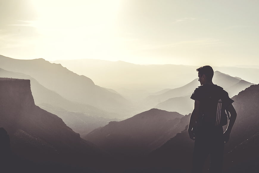 Silhouette of Hiker with Backpack Overlooking Mountain Range