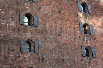 Red brick building facade with arched windows and metal shutters