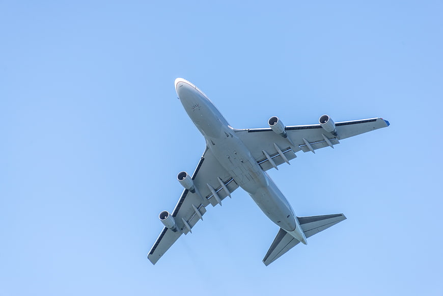 Low angle view of large white airplane flying in blue sky