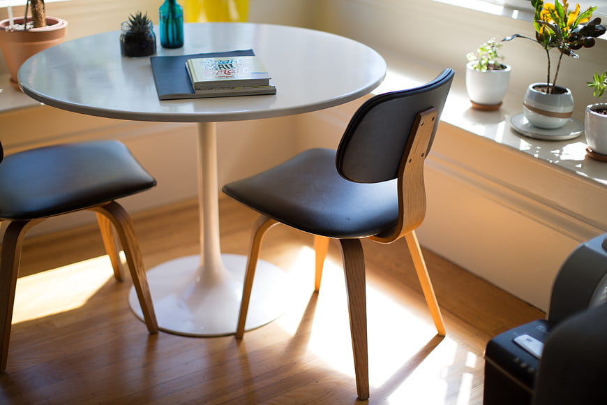 Modern white round table with black chairs and plants