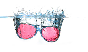 Pink sunglasses splashing into water on white background