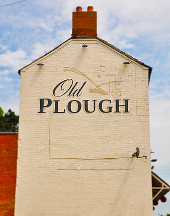 Old Plough pub sign on white brick building facade