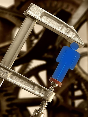Blue figure under metal clamp representing pressure and oppression