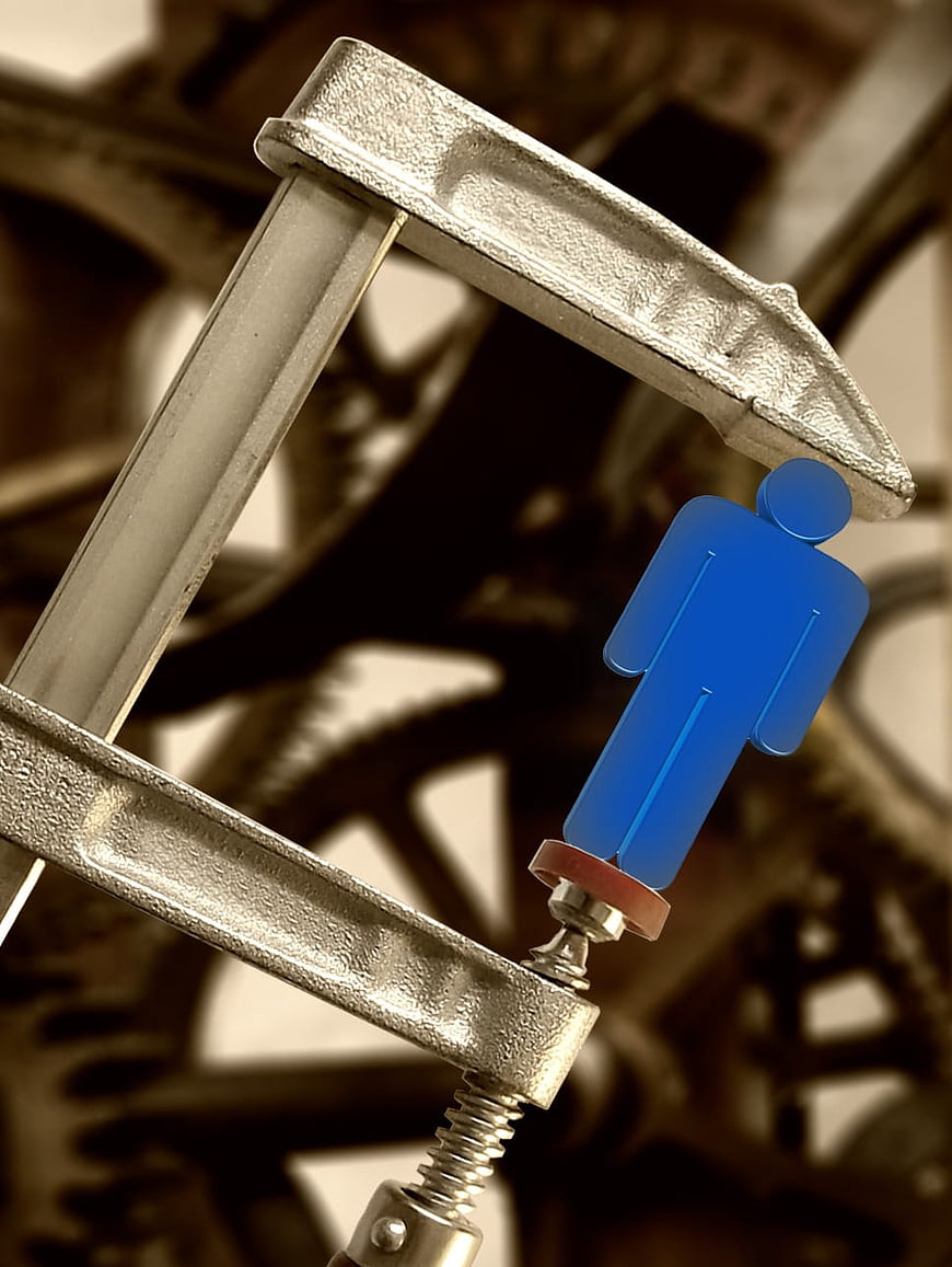Blue figure under metal clamp representing pressure and oppression