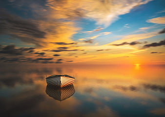 Solitary wooden boat on calm water at golden sunset