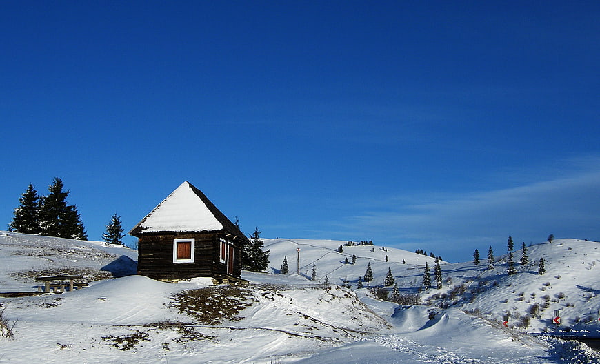 Rustic wooden cabin in snowy winter mountain landscape