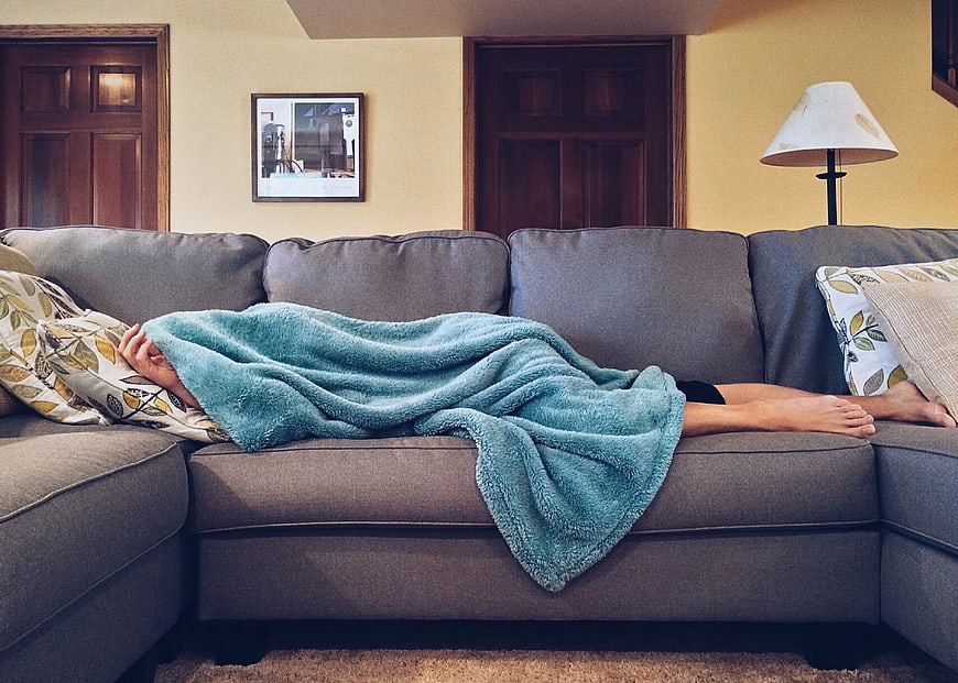 Person Sleeping on Sofa Under Teal Blanket