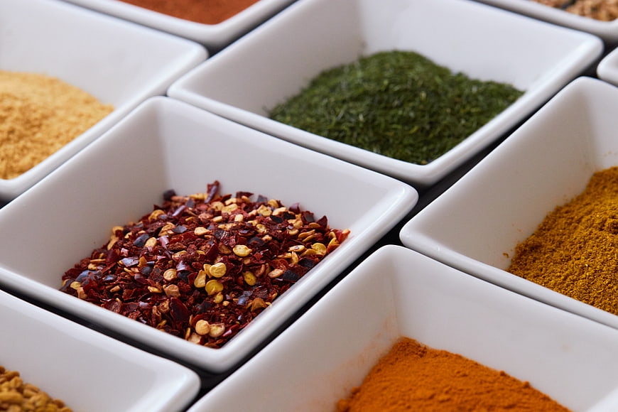 Assorted colorful spices in white square bowls