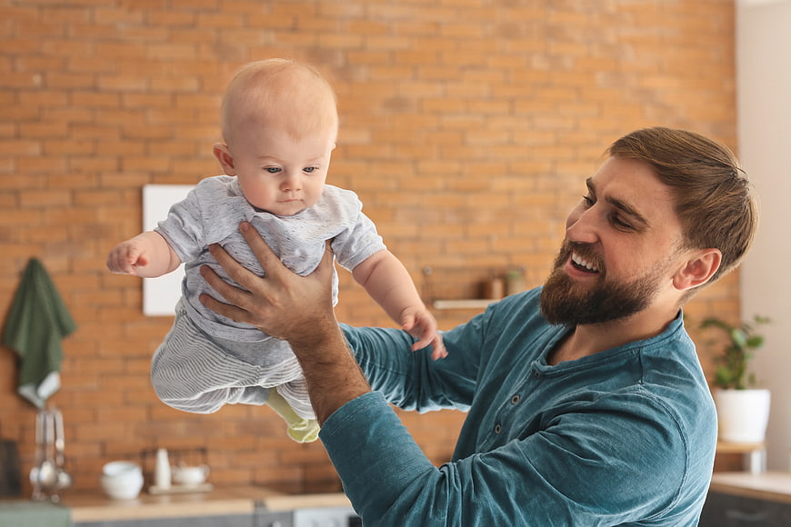 Happy Father Playing with Baby in Modern Kitchen