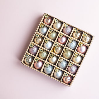 Box of Glittery Christmas Ornaments on Pink Background