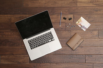 Flat lay of laptop, notebook, and office supplies on wooden desk