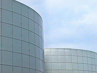 Modern curved glass building facade against blue sky