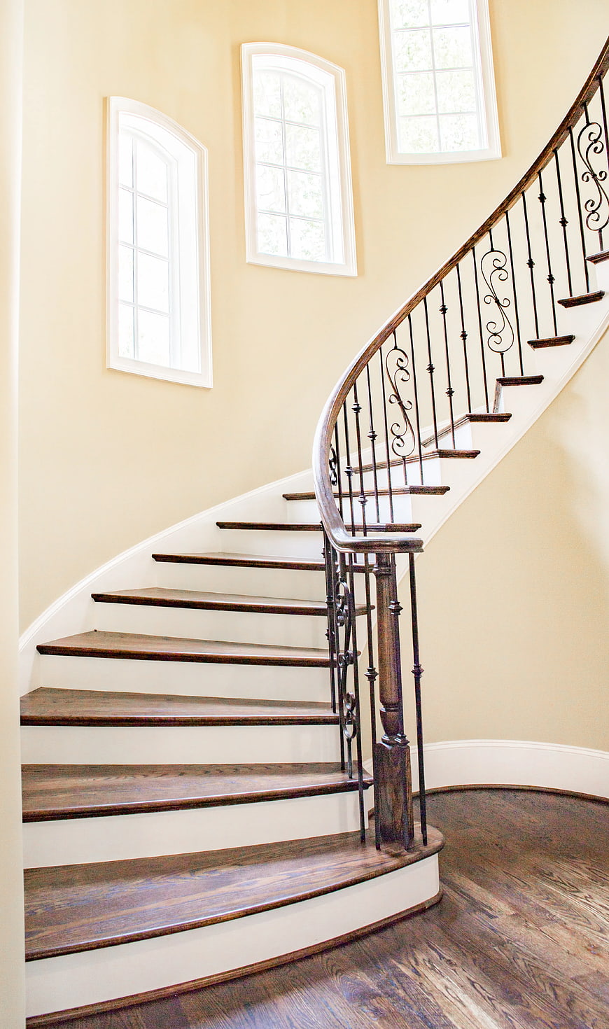 Elegant curved wooden staircase with wrought iron railing