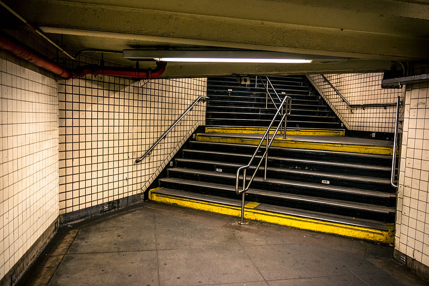 Empty Subway Staircase With White Tiled Walls And Yellow Safety Edges