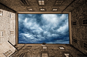 Dramatic cloudy sky framed by stone building courtyard
