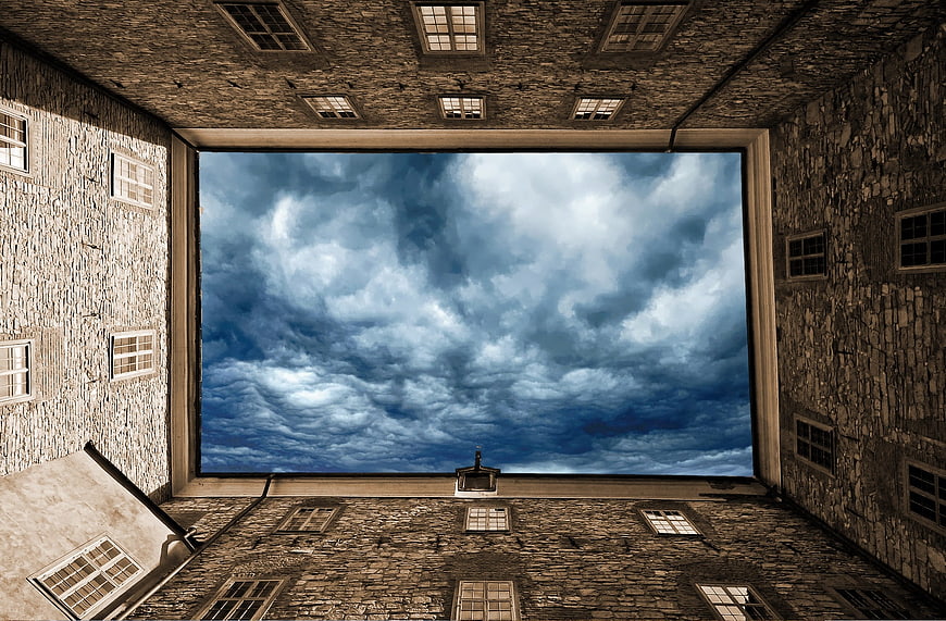 Dramatic cloudy sky framed by stone building courtyard