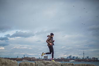 Woman Running on Rocks with Toronto Skyline Background