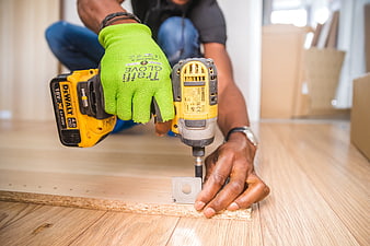 Close-up of a worker using a yellow power drill to assemble furniture