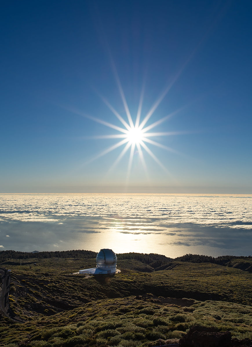Aerial View of Observatory Above Clouds with Sunburst
