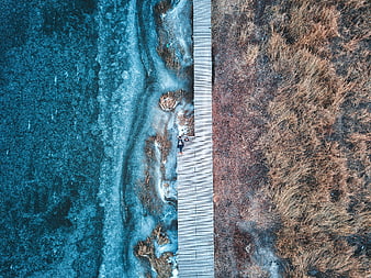 Aerial view of person walking on wooden boardwalk by frozen river