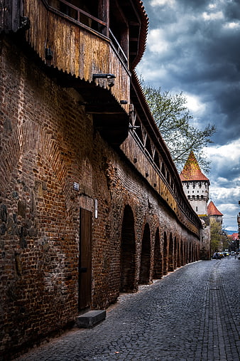 Cobblestone street along historic wooden and brick fortress walls