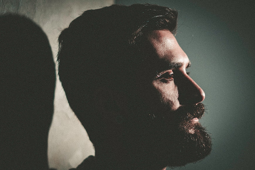 Dramatic profile portrait of bearded man in shadow