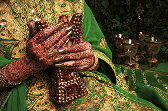 Close-up of hands with intricate henna holding a traditional Indian prayer box