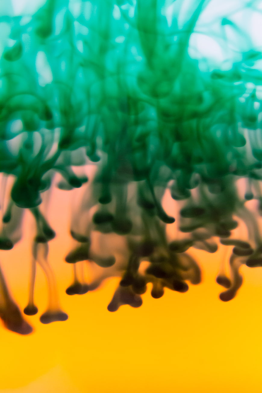 Abstract Green Ink Swirling in Water Over Yellow Background