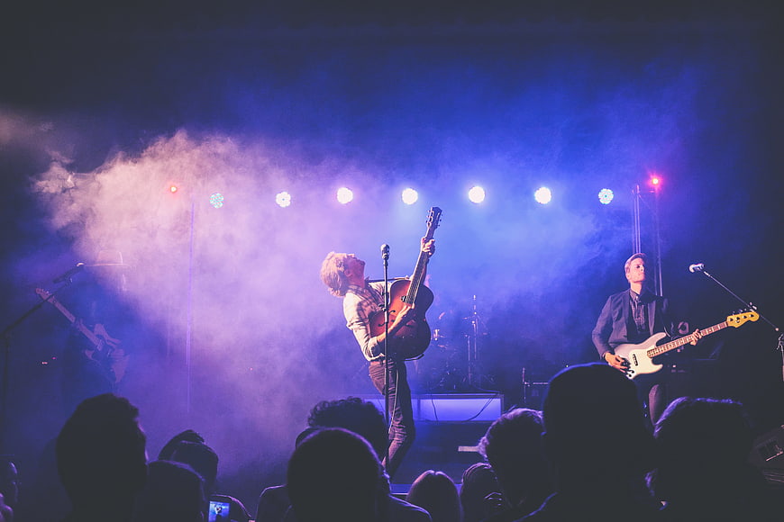 Rock band performing live on stage with blue lights and smoke