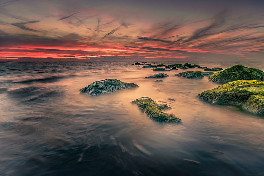 Dramatic Sunset Over Mossy Rocks in the Ocean