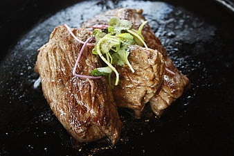 Seared Beef Steak With Fresh Microgreens And Thin Onion Garnish On Dark Plate