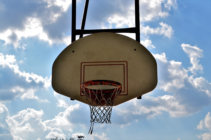 Outdoor Basketball Hoop Against Blue Sky with Clouds
