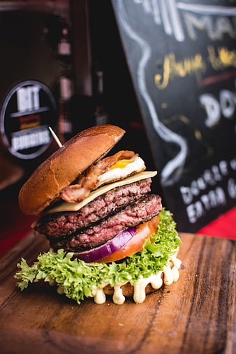 Gourmet double beef burger with egg and bacon on wood