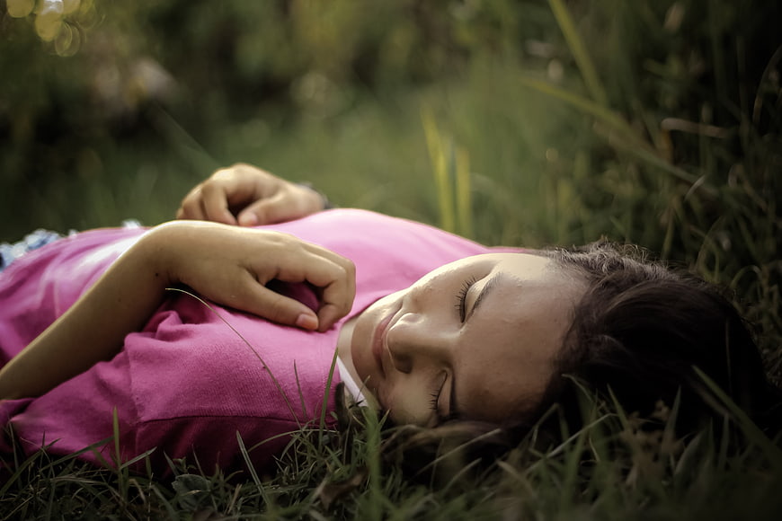 Young woman sleeping peacefully in green grass