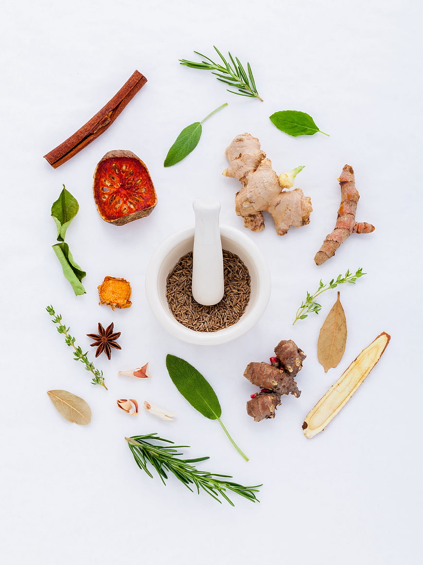 Flat lay of fresh herbs, spices, and mortar on white background