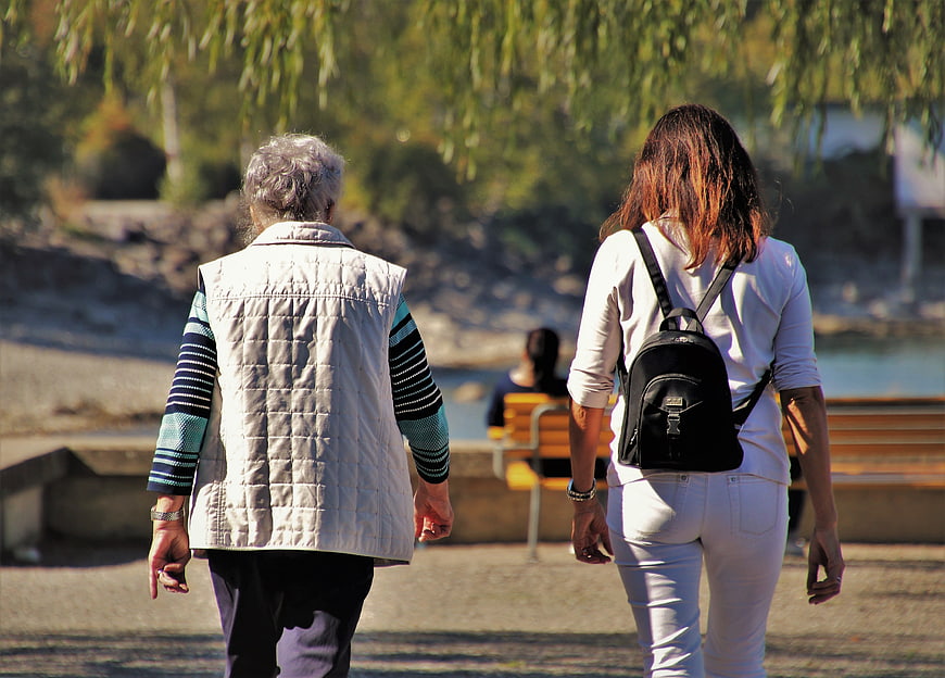 Senior Woman And Young Woman Walking Together In Park