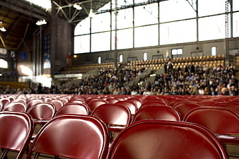 Red Chairs in Indoor Stadium with Blurred Crowd Background