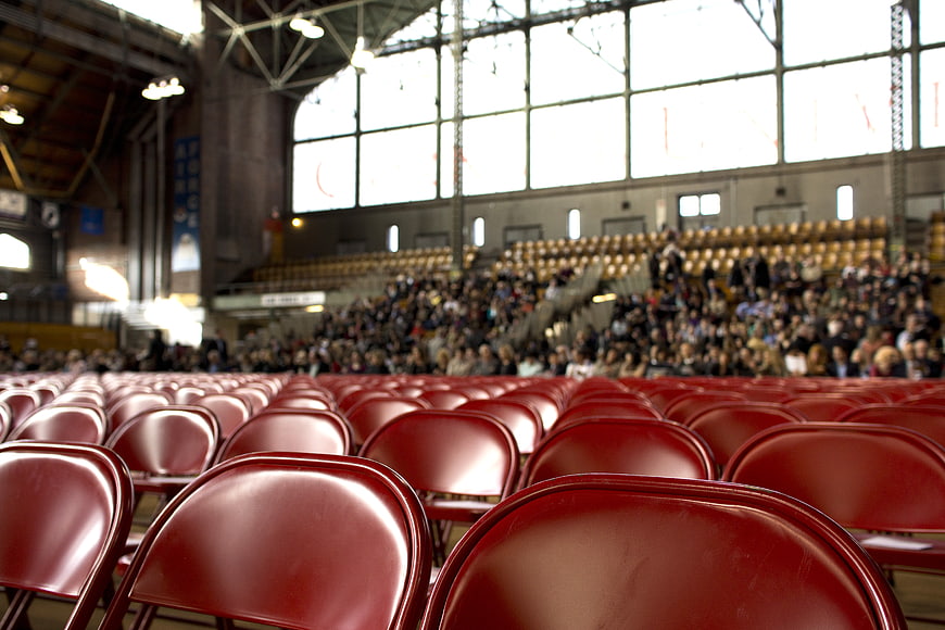 Red Chairs in Indoor Stadium with Blurred Crowd Background