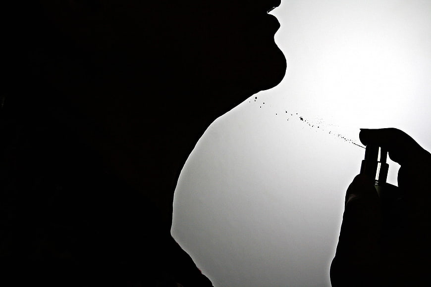Silhouette of woman spraying perfume mist