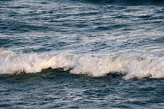Crashing ocean wave with white foam on blue water